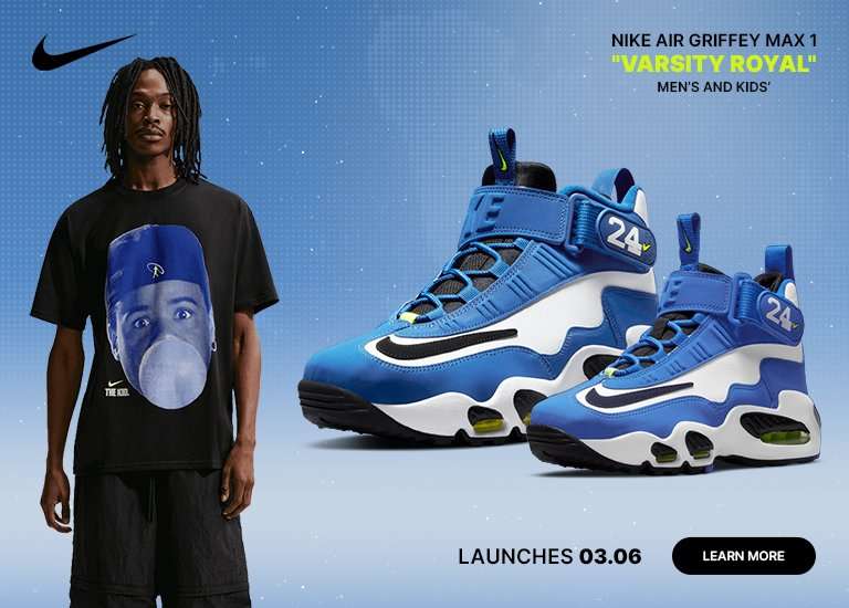A promotional graphic for the Nike Air Griffey Max 1 Varsity Royal launching on 03/06 for men’s and kids’. The image features a man wearing a black The Kid graphic tee and black cargo pants standing next to two pairs of the royal blue, white, and black sneakers against a light blue background.