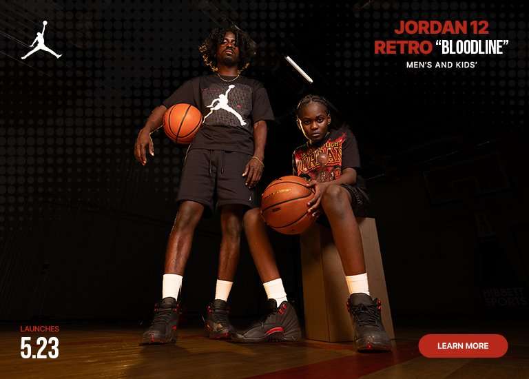 Promotional banner for the Jordan 12 Retro Bloodline launch on 5.23, featuring men's and kids' sizing. A man and a child pose with basketballs against a dark, textured background, alongside a close-up shot of the black and red sneakers on-foot.