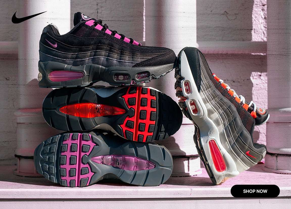 Nike Air Max 95 sneakers in black and gray with pink and orange accents, stacked on display with visible Air cushioning and outsole details.