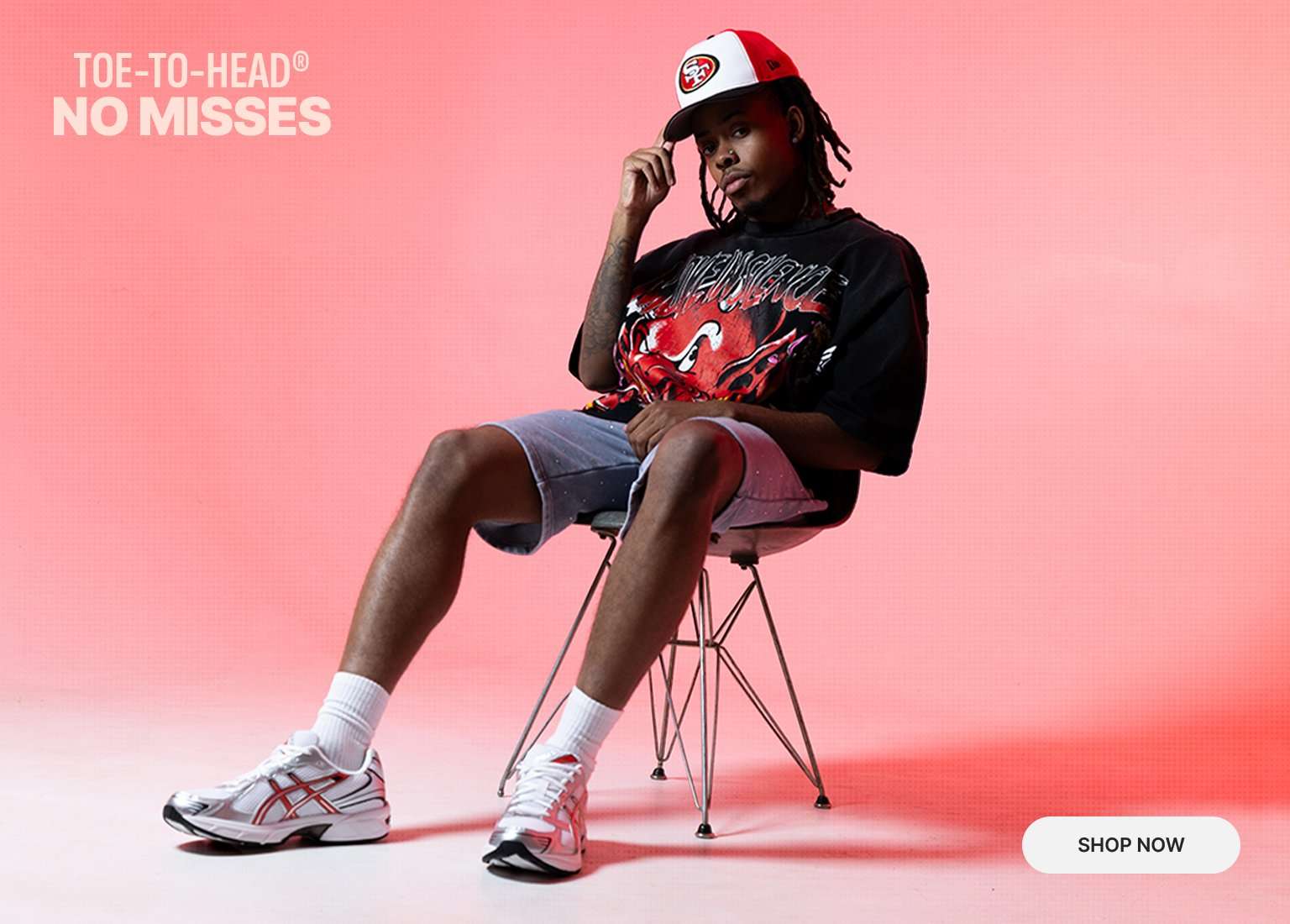 A person sits in a chair wearing a black graphic tee, grey shorts, a San Francisco 49ers hat, and white Asics GEL-1130 sneakers with red accents against a pink background. Text in the upper left reads TOE-TO-HEAD NO MISSES.