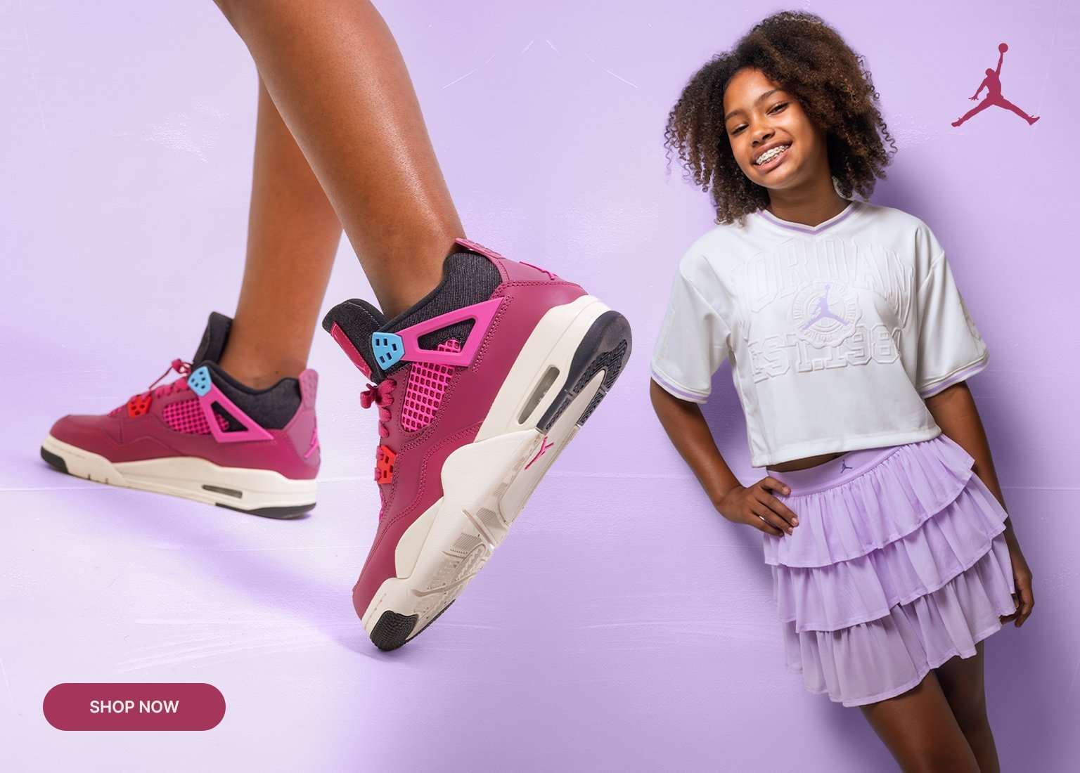 Girls' pink Air Jordan 4 sneakers paired with white Jordan apparel and a lavender skirt on a light purple background.