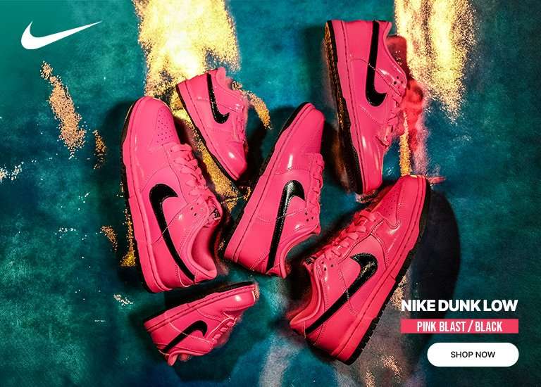 Several pairs of Nike Dunk Low Pink Blast and Black sneakers are scattered across a textured blue and gold background. A white Nike swoosh is in the top left, while the bottom right features the text NIKE DUNK LOW PINK BLAST / BLACK above a white SHOP NOW button.