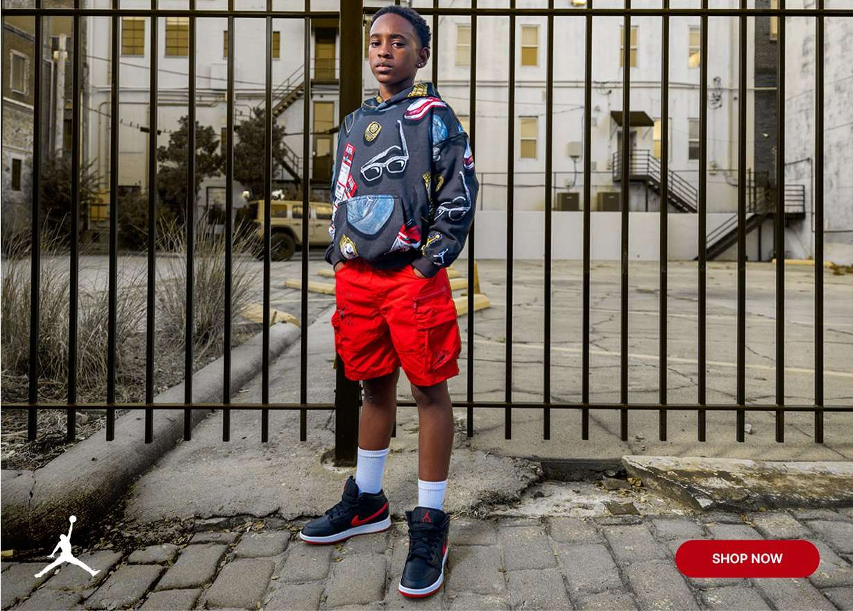 Kids' outfit featuring Air Jordan 1 Mid sneakers, graphic hoodie and red cargo shorts.