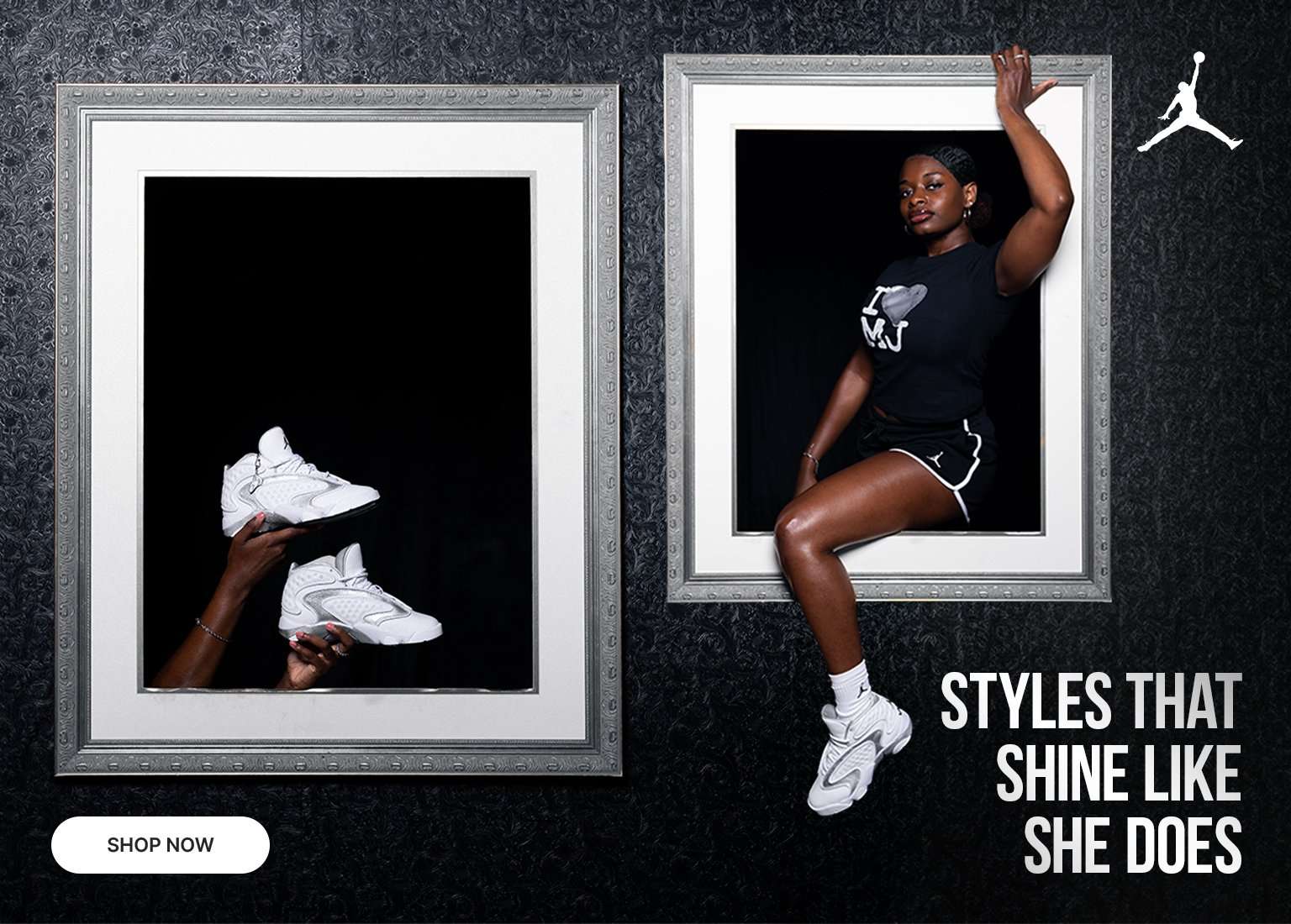 A Jordan Brand advertisement featuring two large ornate picture frames against a black textured wallpaper background. Inside the left frame, two hands hold up a pair of white and silver sneakers against a black backdrop. Inside the right frame, a woman in a black Jordan T-shirt and shorts poses as if stepping out of the frame, wearing the matching white sneakers. The top right corner features the white Jumpman logo, the bottom right displays the text STYLES THAT SHINE LIKE SHE DOES, and a SHOP NOW button sits in the bottom left corner.