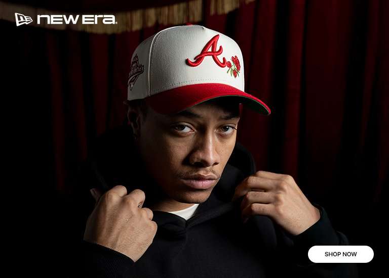 A promotional banner for the New Era Hearts Collection features three stylized portraits of a model wearing different baseball caps against a dark red velvet curtain. The hats include a white and red Atlanta Braves cap with a rose embroidery, a red and pink New York Yankees cap with a heart, and a white and black Yankees cap also featuring a rose.