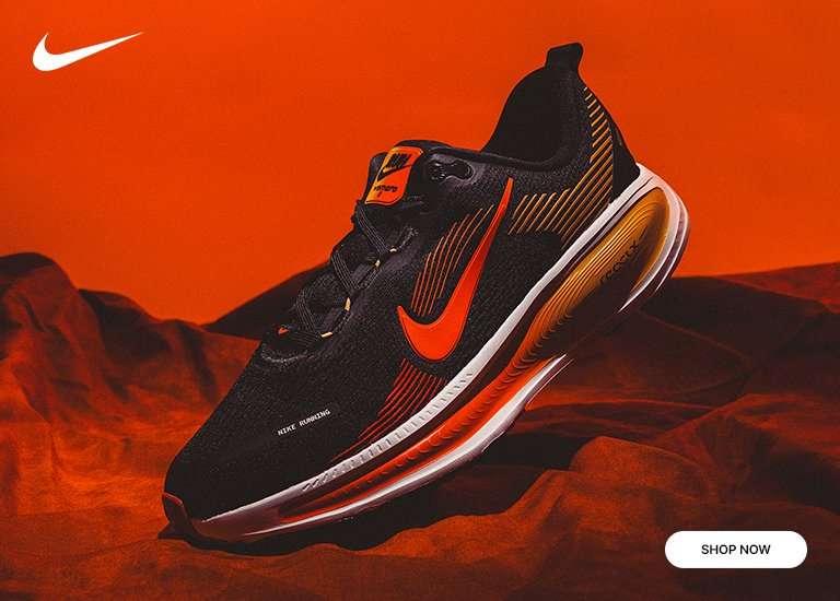 A promotional image for the Nike Vomero 18 running shoe, featuring a black sneaker with vibrant orange and yellow accents against a warm, textured background. The Shop Now button is in the bottom right corner.