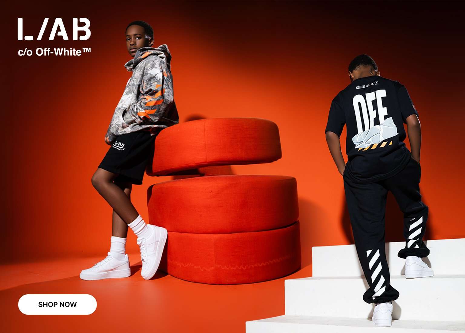 Youth models wearing L/A/B c/o Off-White apparel, including a graphic hoodie, T-shirt, and joggers, posed against a bright orange studio backdrop.