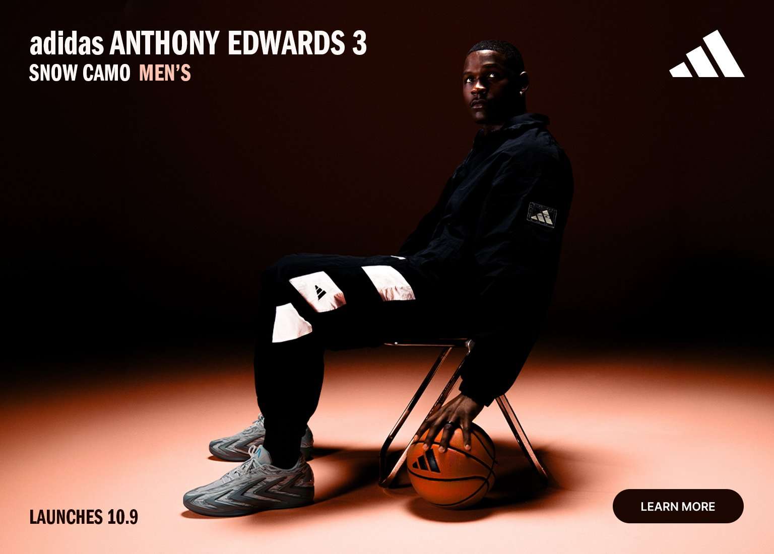 adidas Anthony Edwards 3 Snow Camo basketball shoes with athlete seated on a chair holding a basketball in a dark studio setting.