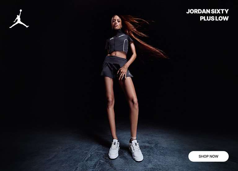 A Jordan promotional banner set against a solid black background features a woman modeling athletic apparel on the left and a hand holding up a shoe on the right. The woman wears a dark gray, short-sleeved crop top with white trim and a matching pleated skirt. A hand prominently displays the Jordan Sixty Plus Low sneaker, which features a white and gray upper with black accents and a visible Air unit in the heel. A white Jumpman logo is positioned in the top left corner, text in the top right reads JORDAN SIXTY PLUS LOW, and a white SHOP NOW button is in the bottom right corner.