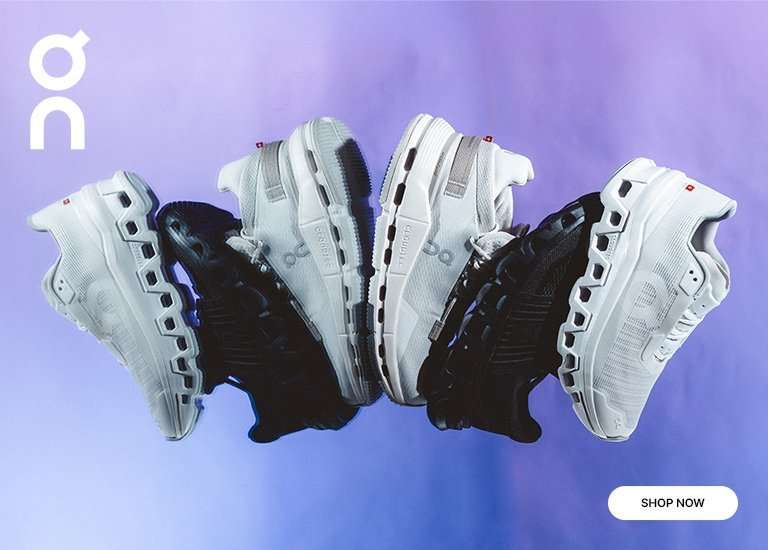 Two pairs of On running shoes—one black and one white—stacked on a reflective purple and blue surface.