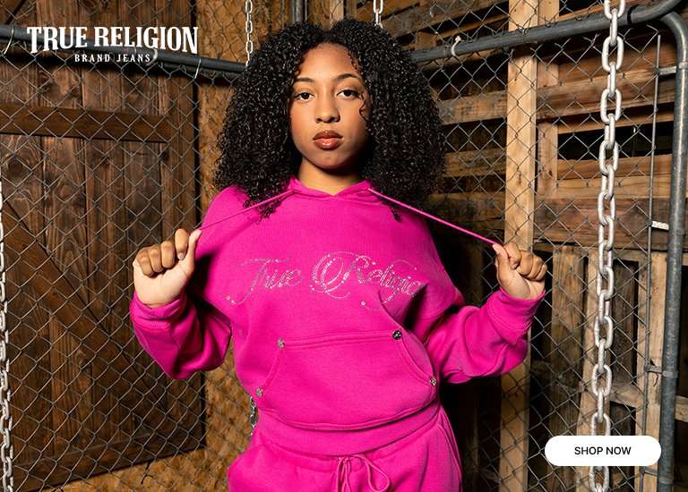 A young woman in a bright pink True Religion hoodie and matching bottoms. Displays the True Religion logo as well as a Shop Now button.