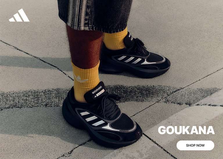 A person wearing yellow Adidas socks and black Adidas Goukana sneakers stands on a concrete surface. The Adidas logo is in the top left, with the text 'GOUKANA' and a 'SHOP NOW' button positioned in the bottom right corner.