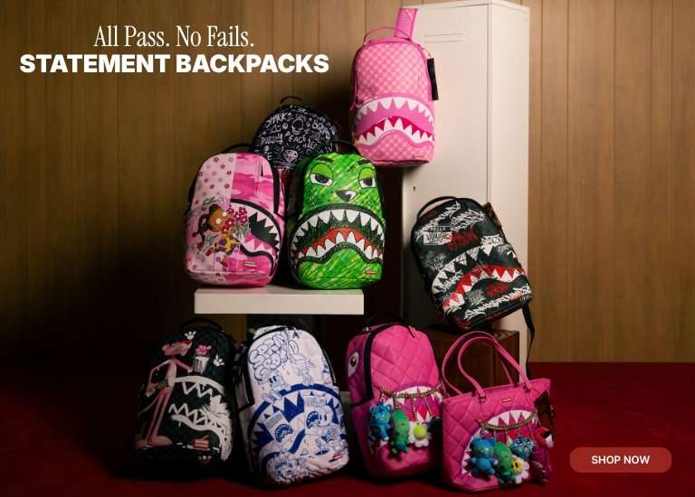 Display of colorful Sprayground statement backpacks and bags with bold graphic designs, including shark-mouth prints, on stacked shelves.