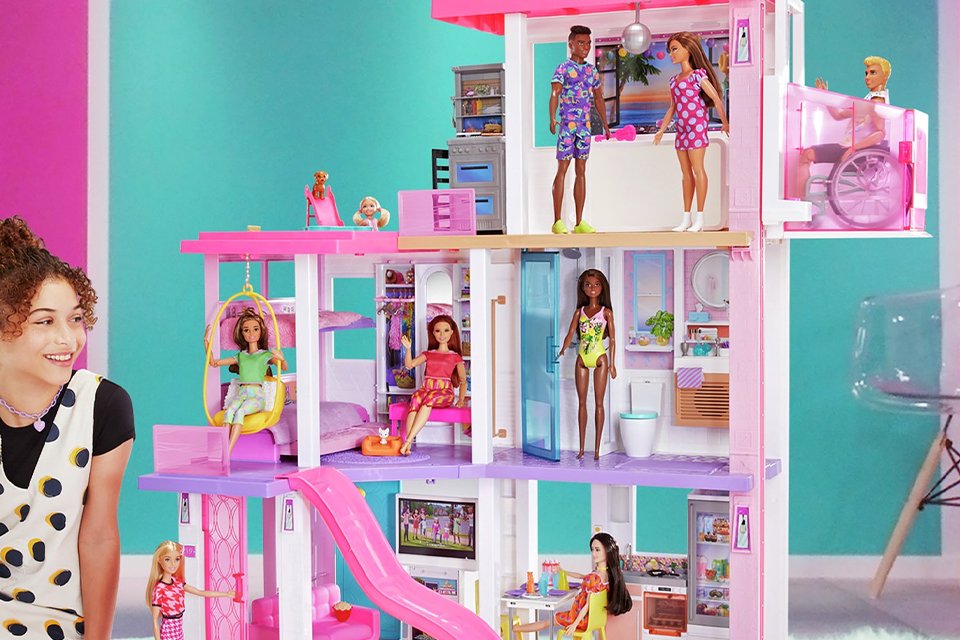 Girl playing with Barbie Day to Night Dreamhouse Dolls House playset.