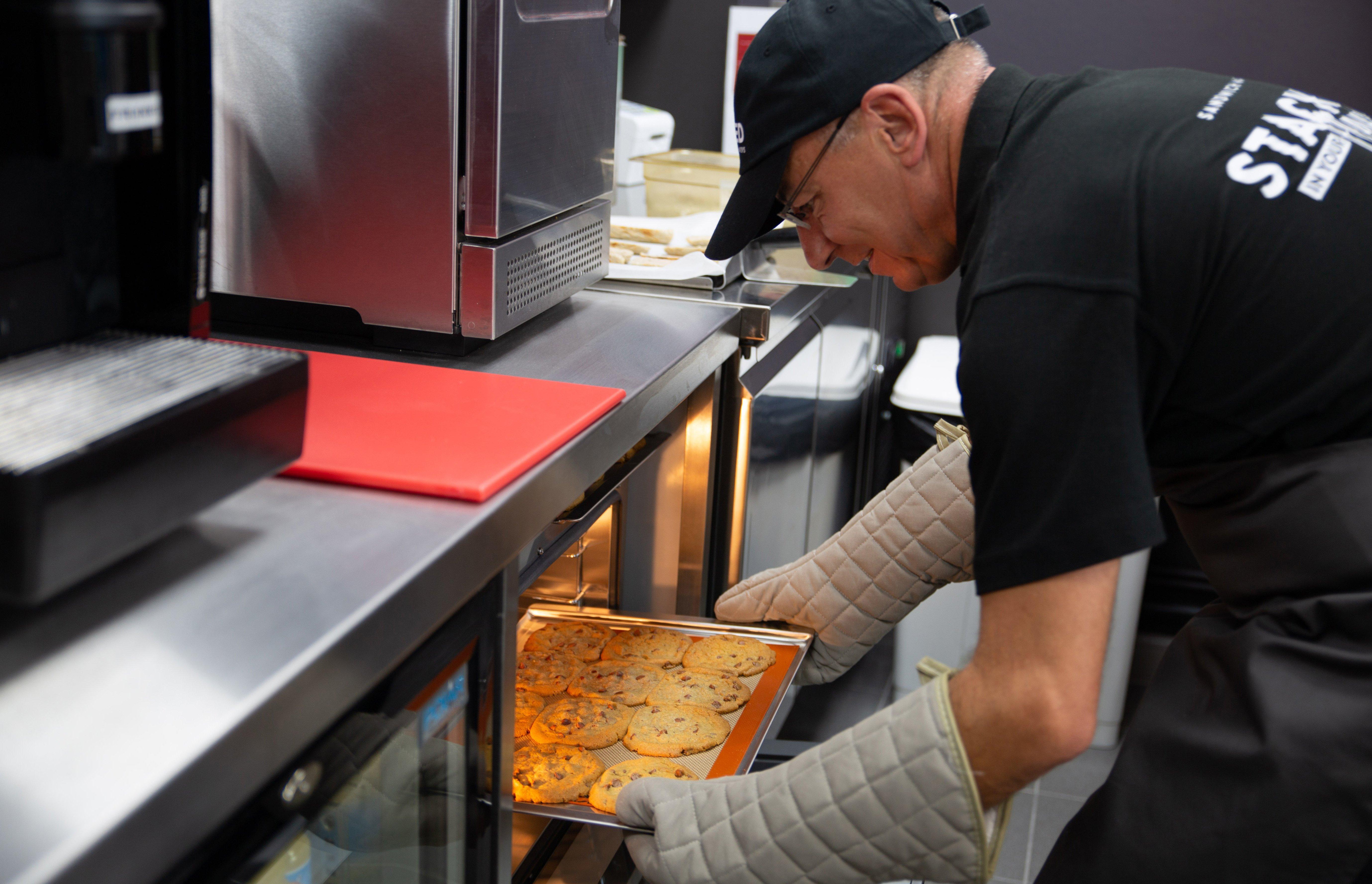 Colleague pulling cookies out of oven