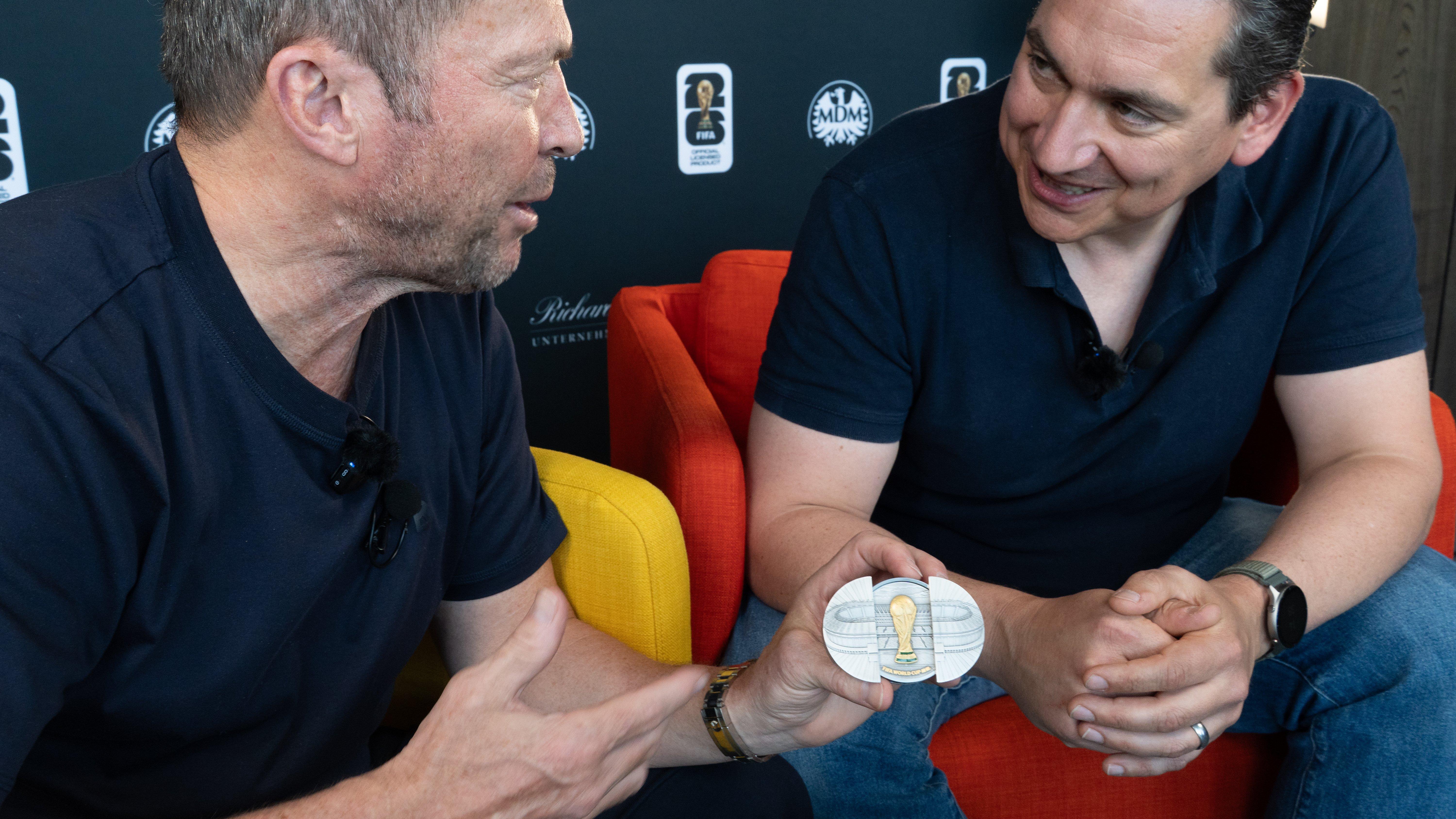 Lothar Matthäus am Tisch mit der Silbermünze mit Schiebetür-Motiv