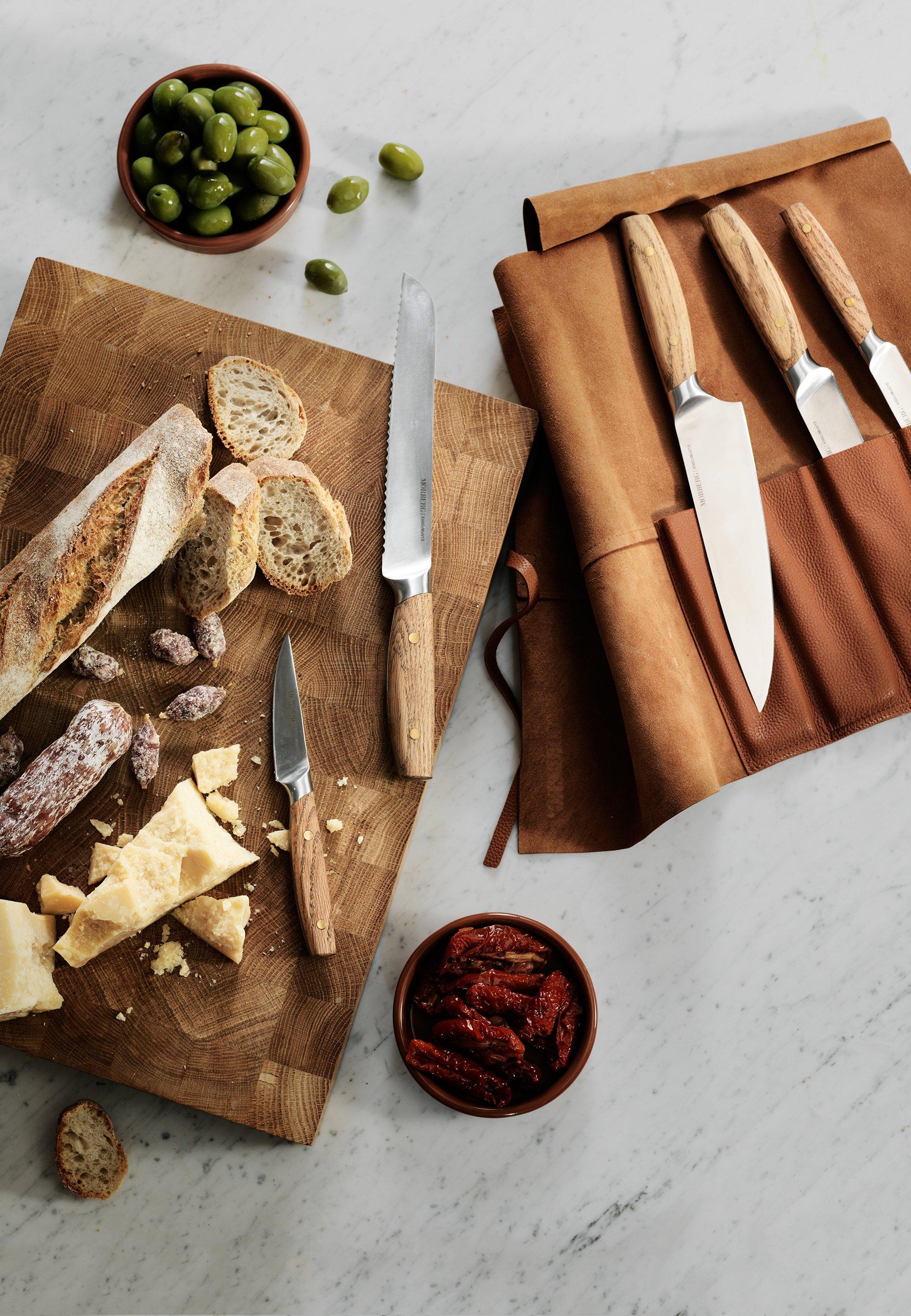 Ett dekorativt bord med brödlimpor och knivar liggandes på skärbrädor