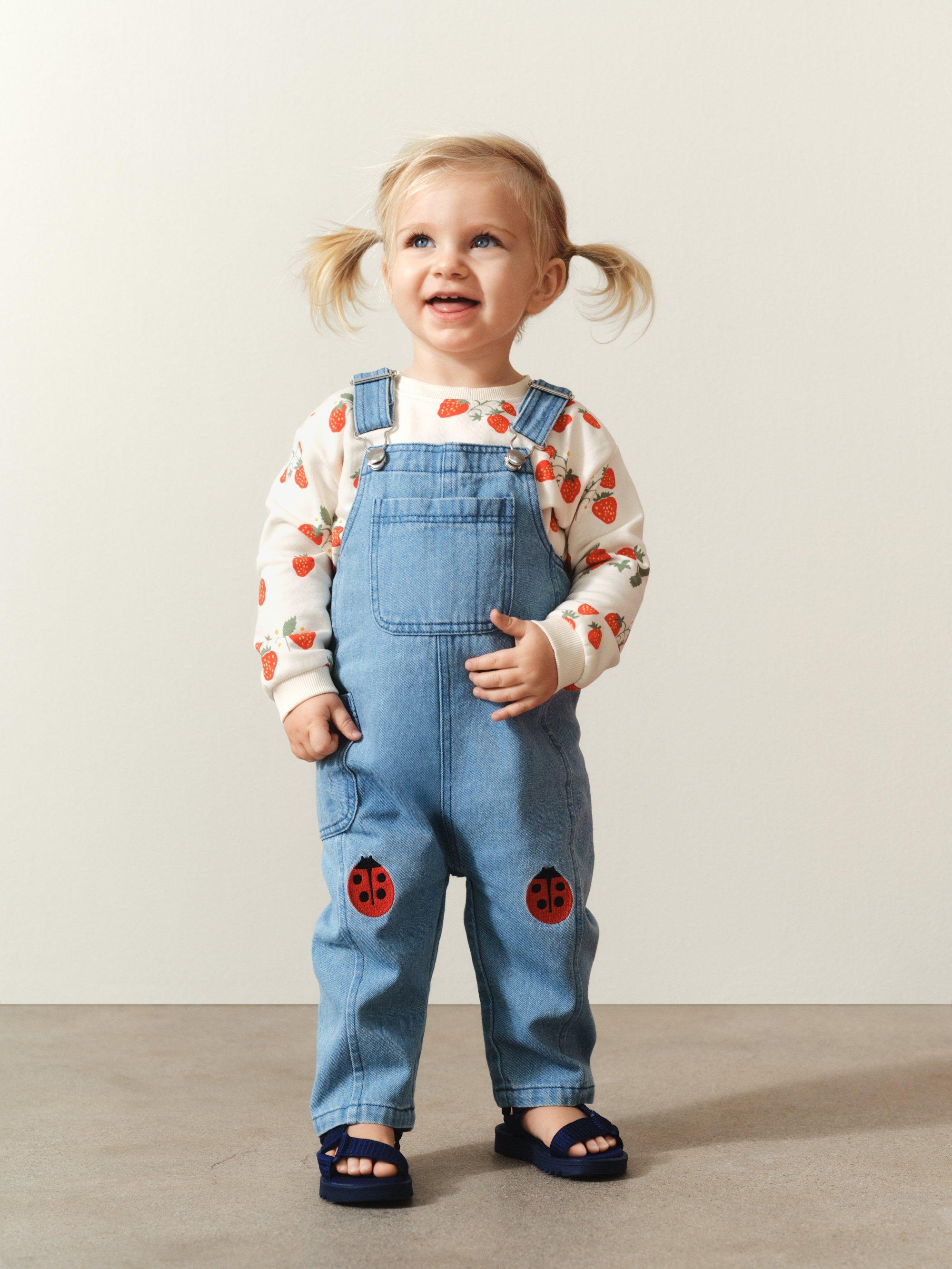 baby som sitter på golvet med en jacka.