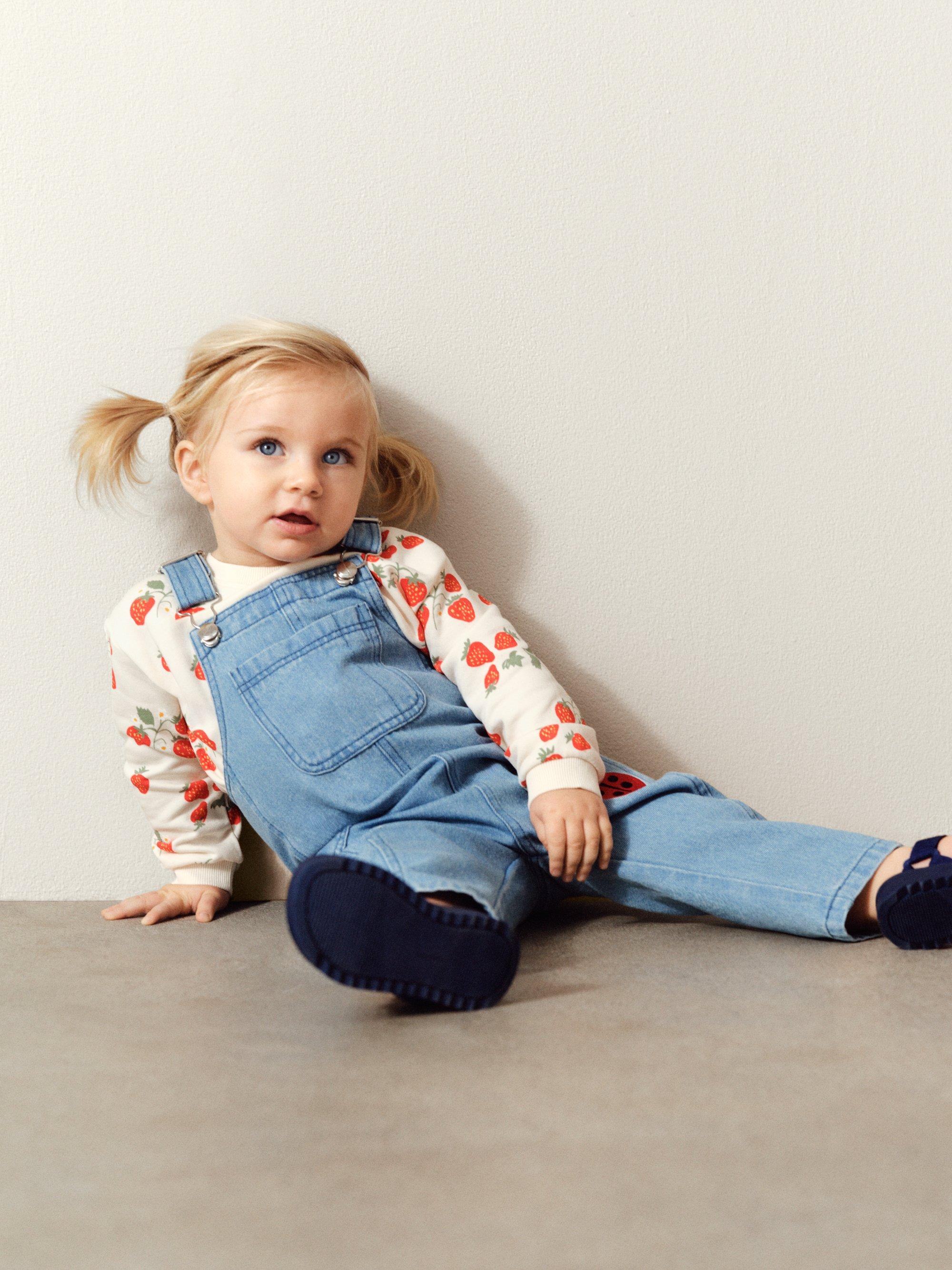 baby i hängselbyxor och blå bakgrund