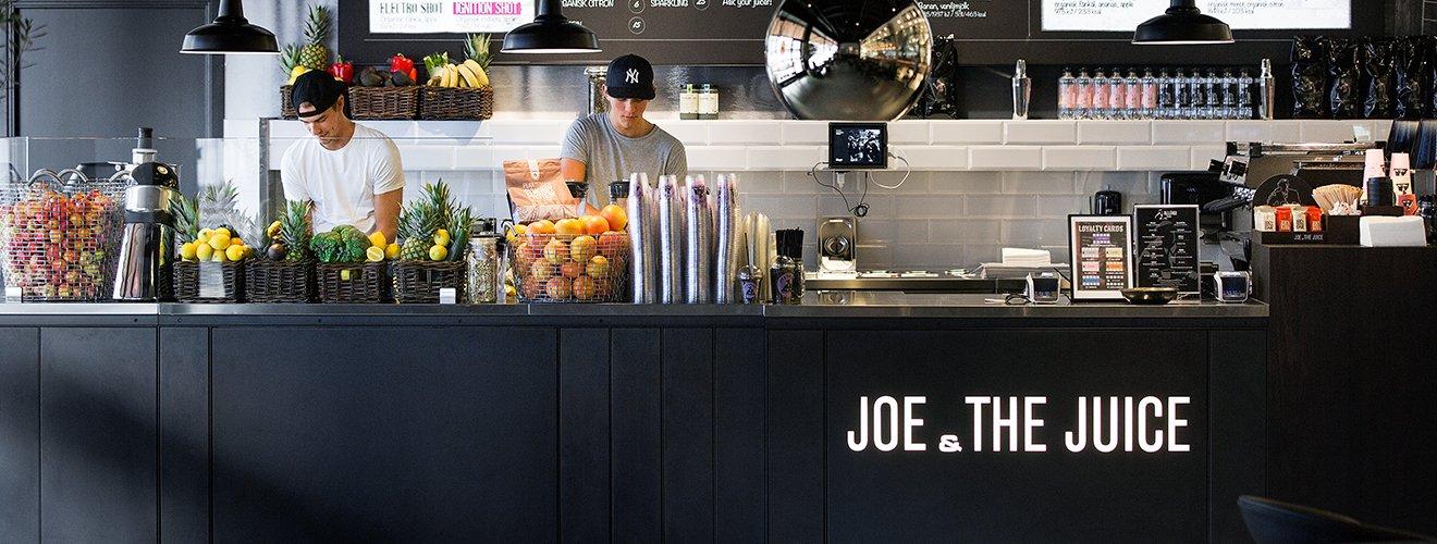 Juicebar hos Joe & The Juice med färsk frukt, juicepress och personal bakom disken.