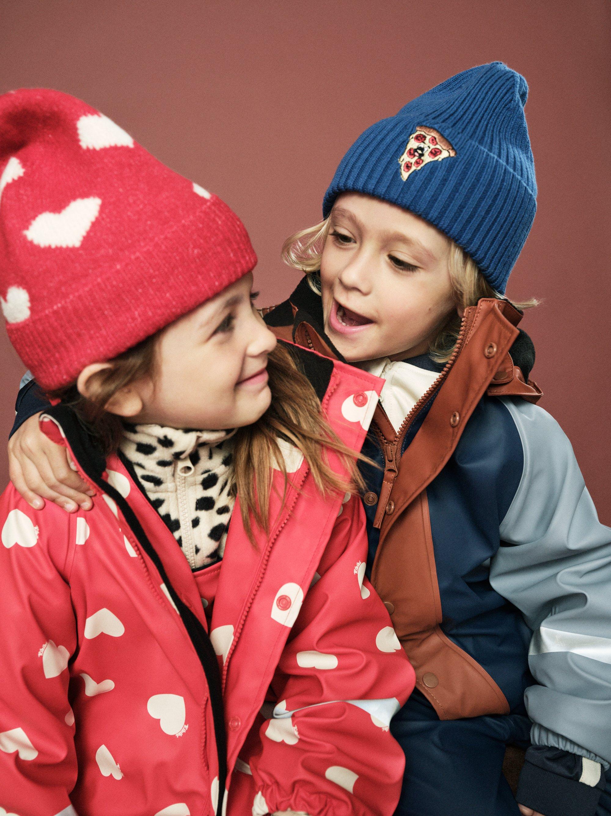 två barn i mössa och ytterplagg.