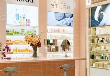 Skönhetsavdelning med hudvårdsprodukter, spegel och upplysta hyllor i butiksmiljö.