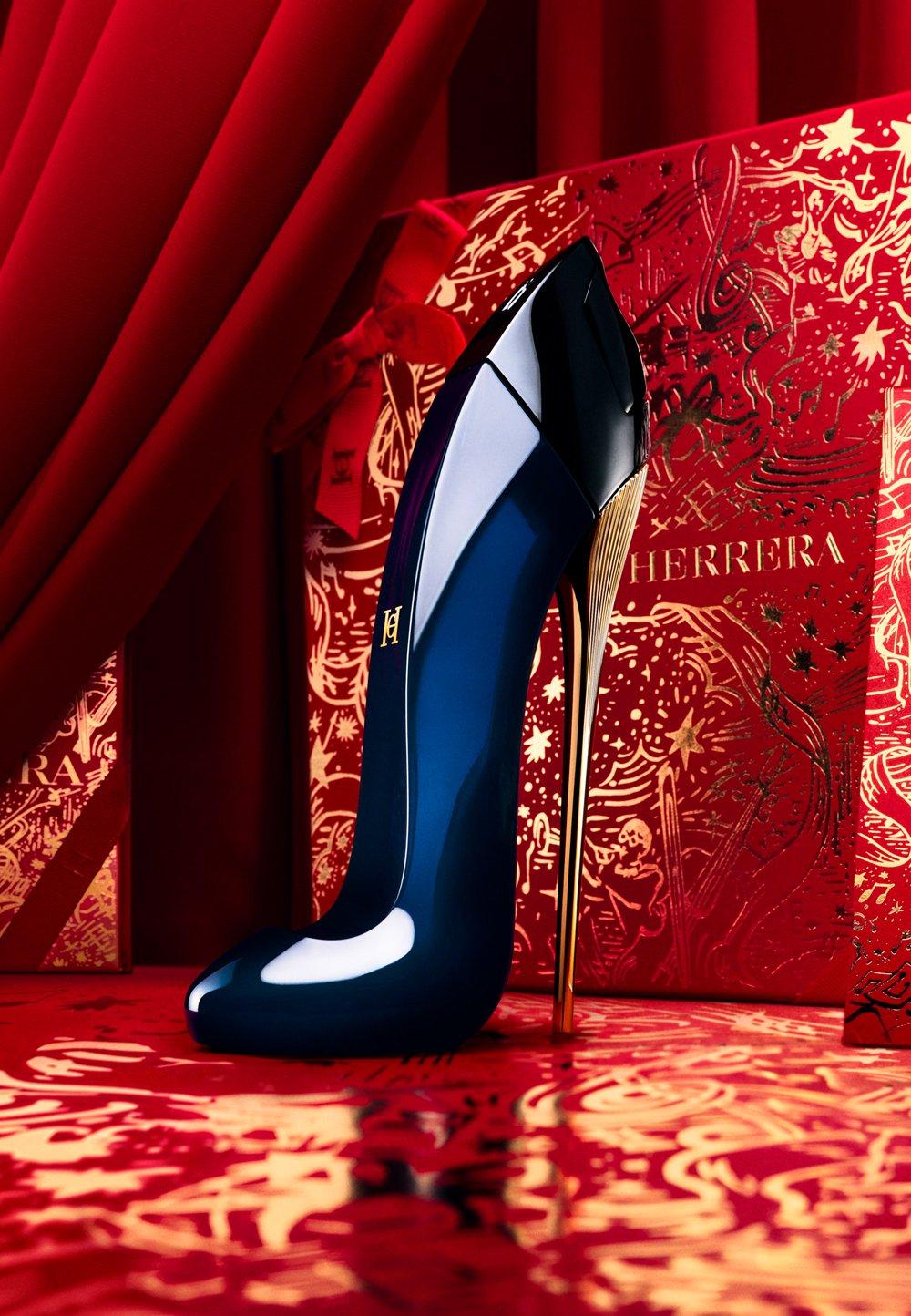 Blå parfymflaska formad som klacksko står på röd-guldigt bord.