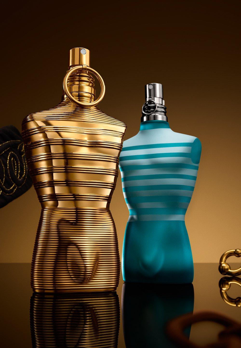 1 guldig och 1 blå parfym står på ett mörkt bord.