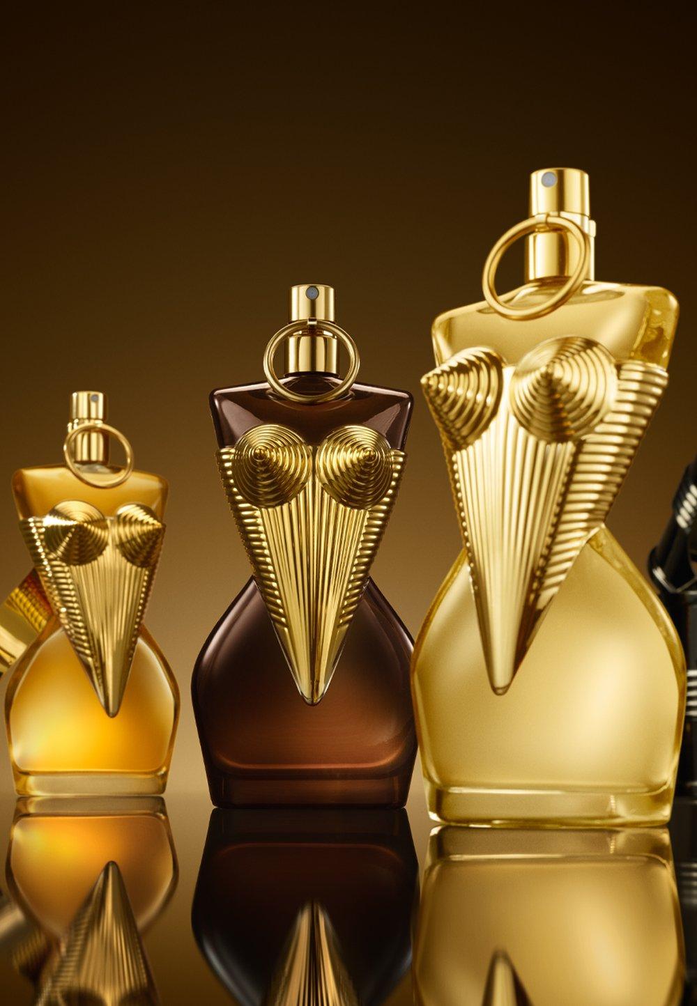 Guldig parfymflaska står på guldig piedestal. 