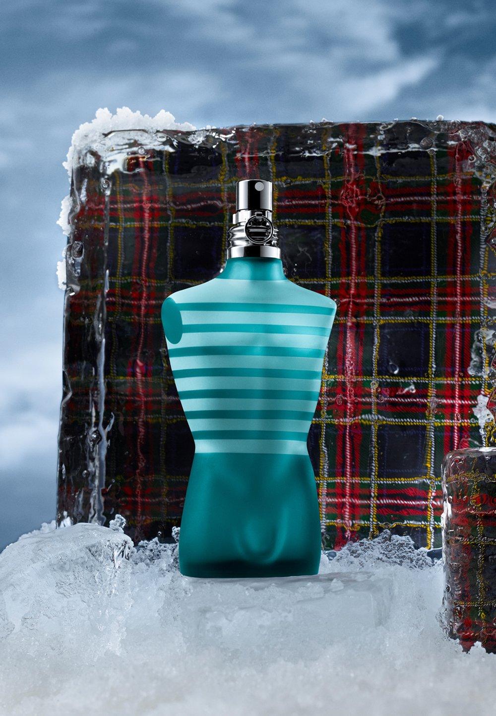 Blå parfymflaska står på is med en rutig pläd.