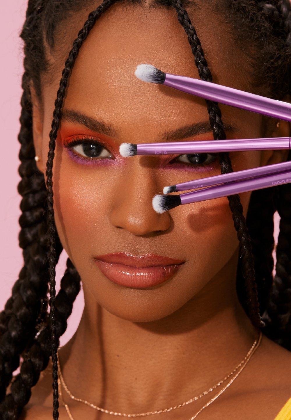 Tjej håller i flera sminkborstar