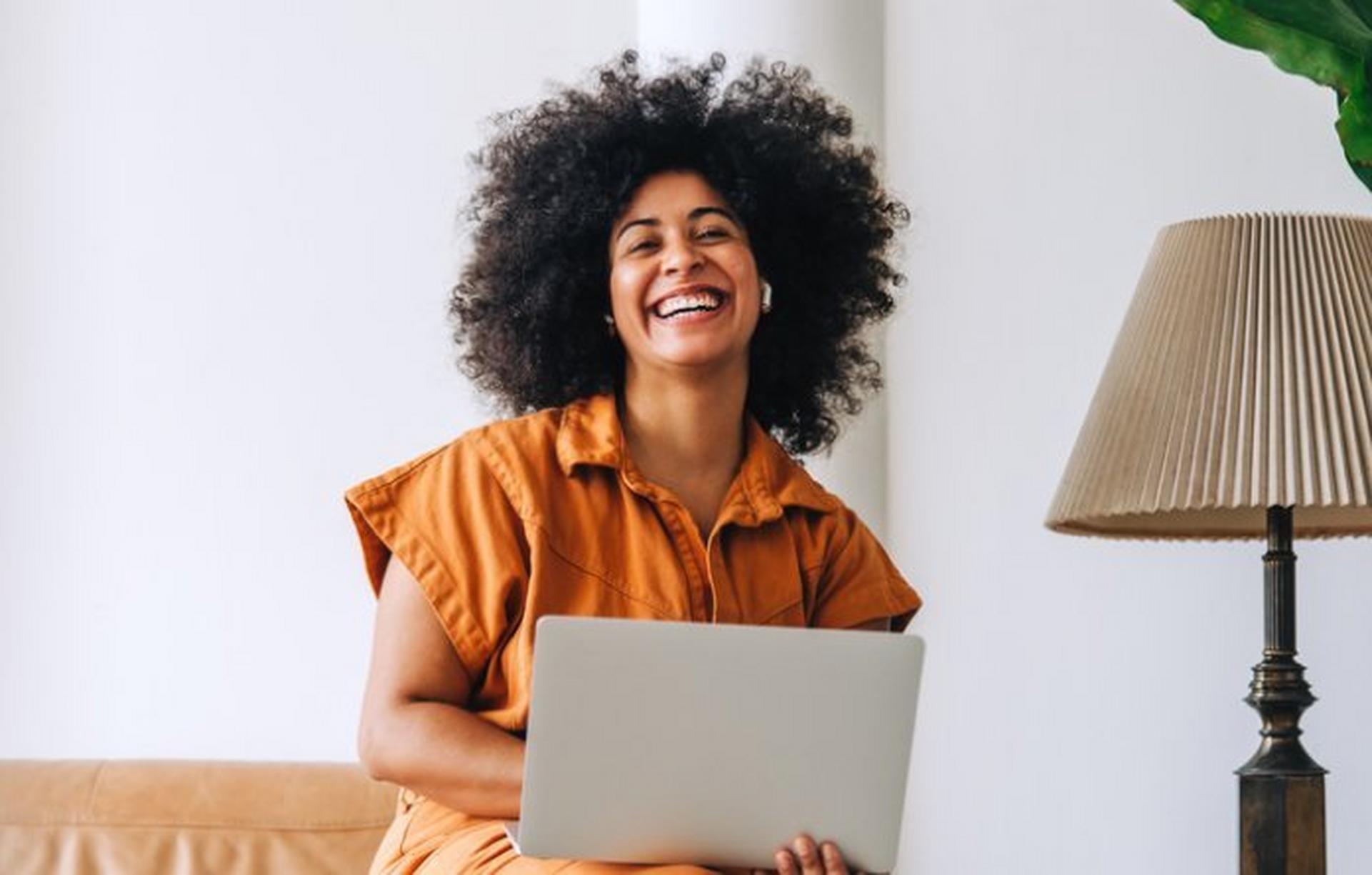 Person in an office laughing with a laptop on their lap