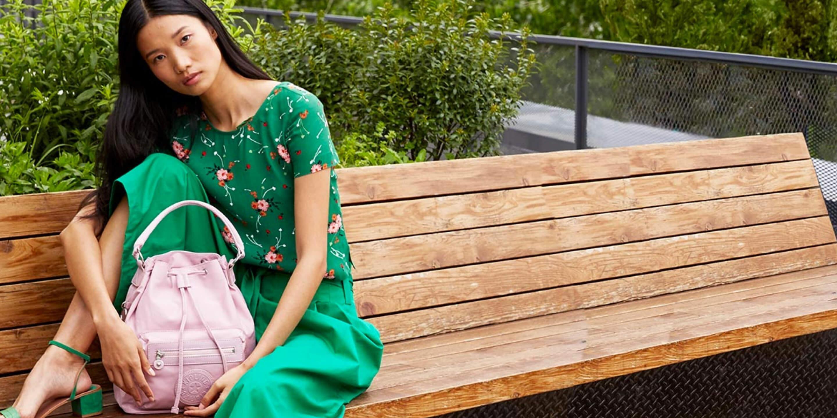 a woman sitting on a bench with a pink purse