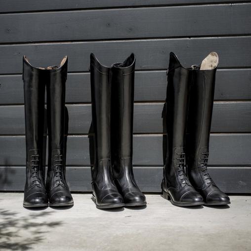 Ariat tall black riding boots stacked against wall