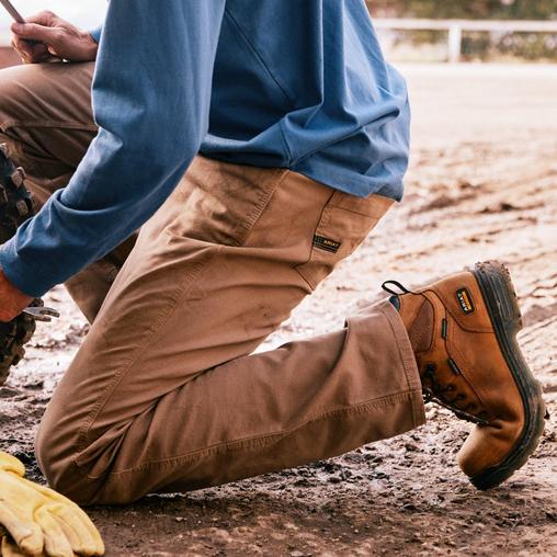 man works in mud in ariat work pants and shoes
