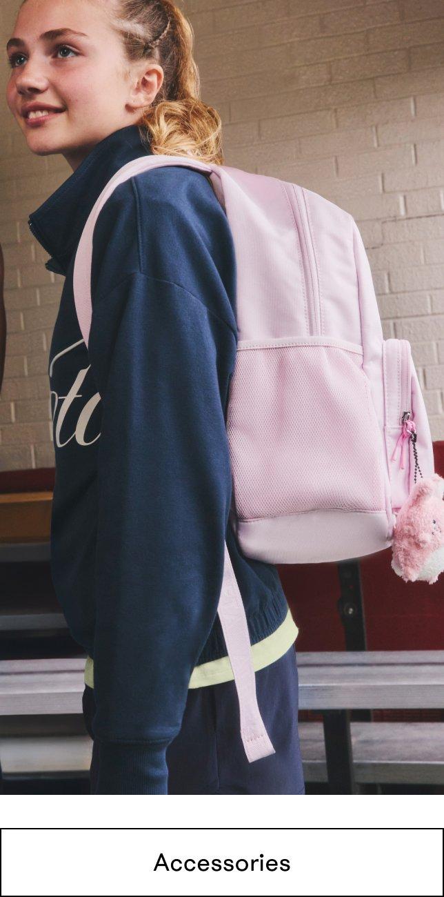a girl with a pink backpack standing next to a wall