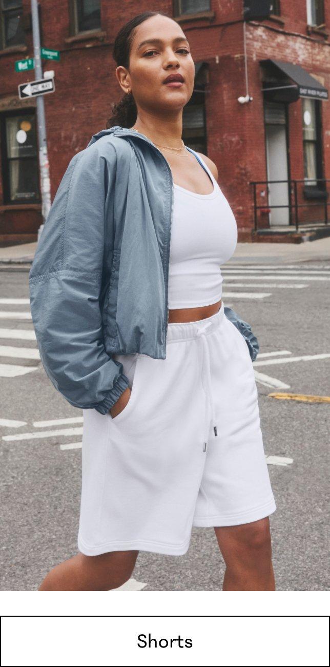 a woman in white top and shorts crossing the street