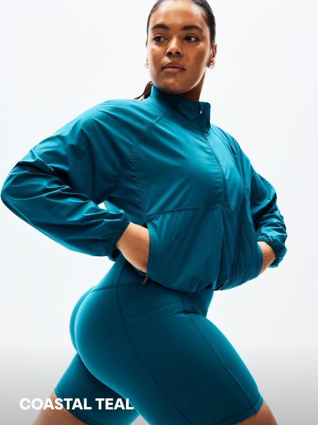 COASTAL TEAL. a woman in a teal jacket and shorts posing