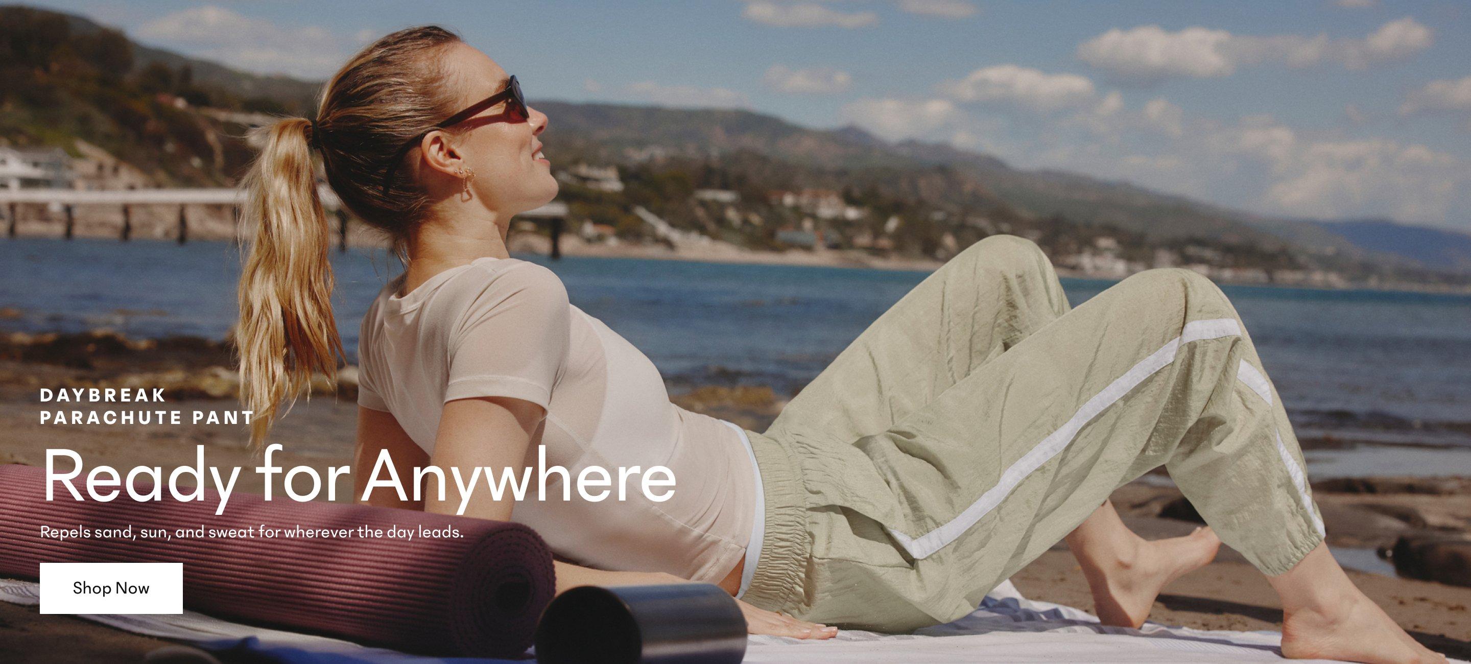 Daybreak Parachute Pant. Ready for Anywhere. Repels sand, sun, and sweat for wherever the day leads. Shop Now. a woman laying on a yoga mat on the beach