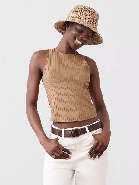 Woman in tan tank top and straw hat.