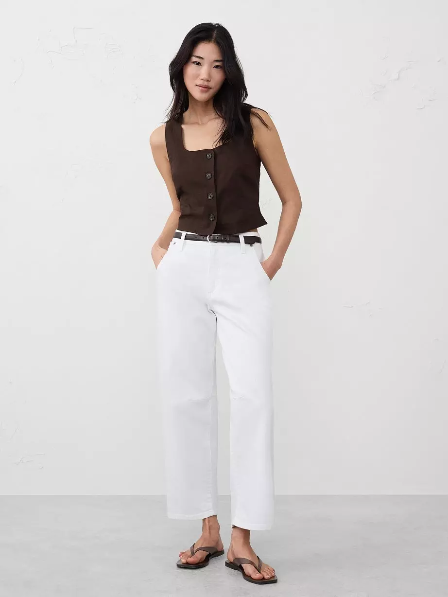 Woman in brown top and white pants.
