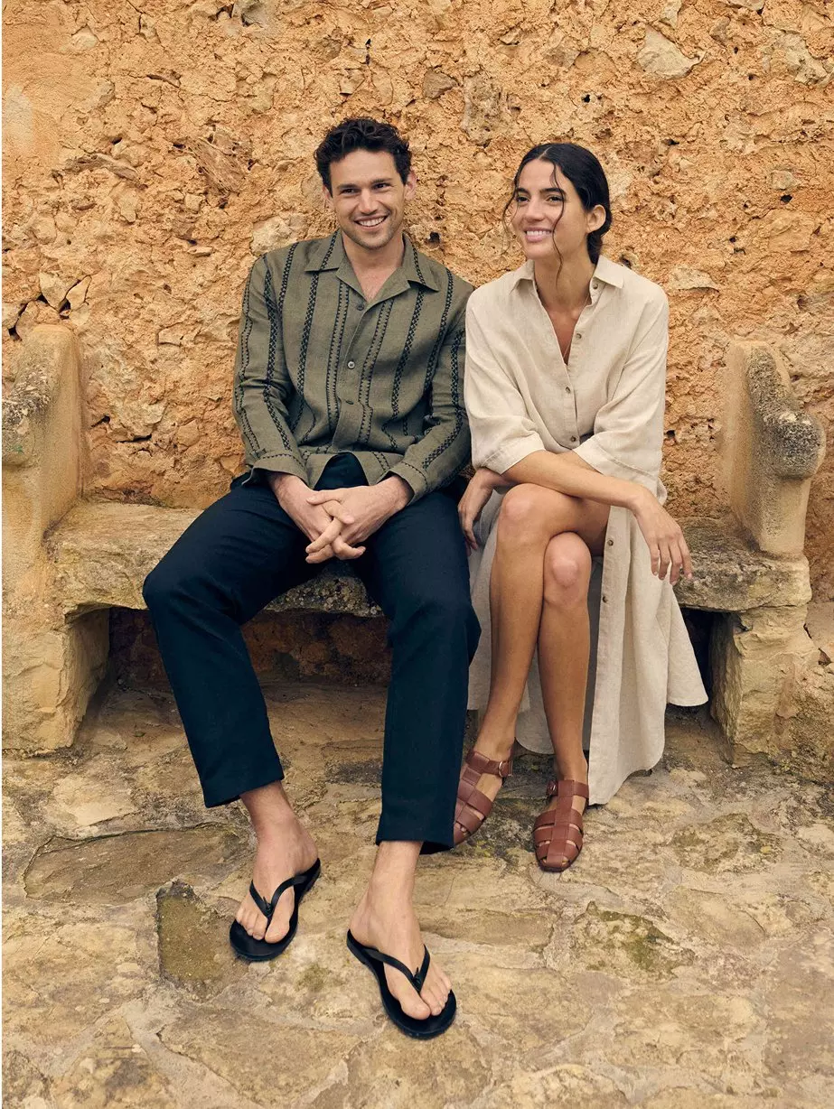 Man with long sleeve striped shirt and black pants.  Woman in long sleeve cream dress.
