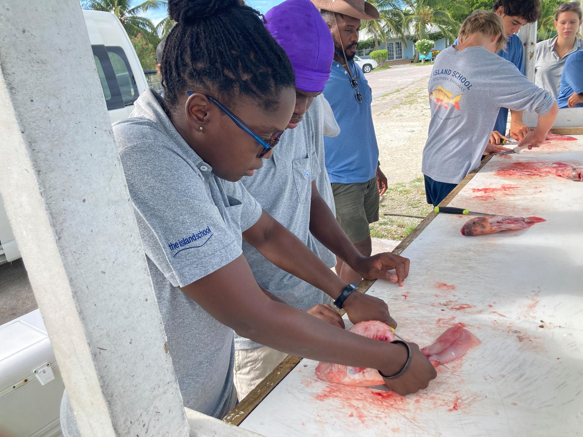 Woman teaching a yourng man how to clean fish