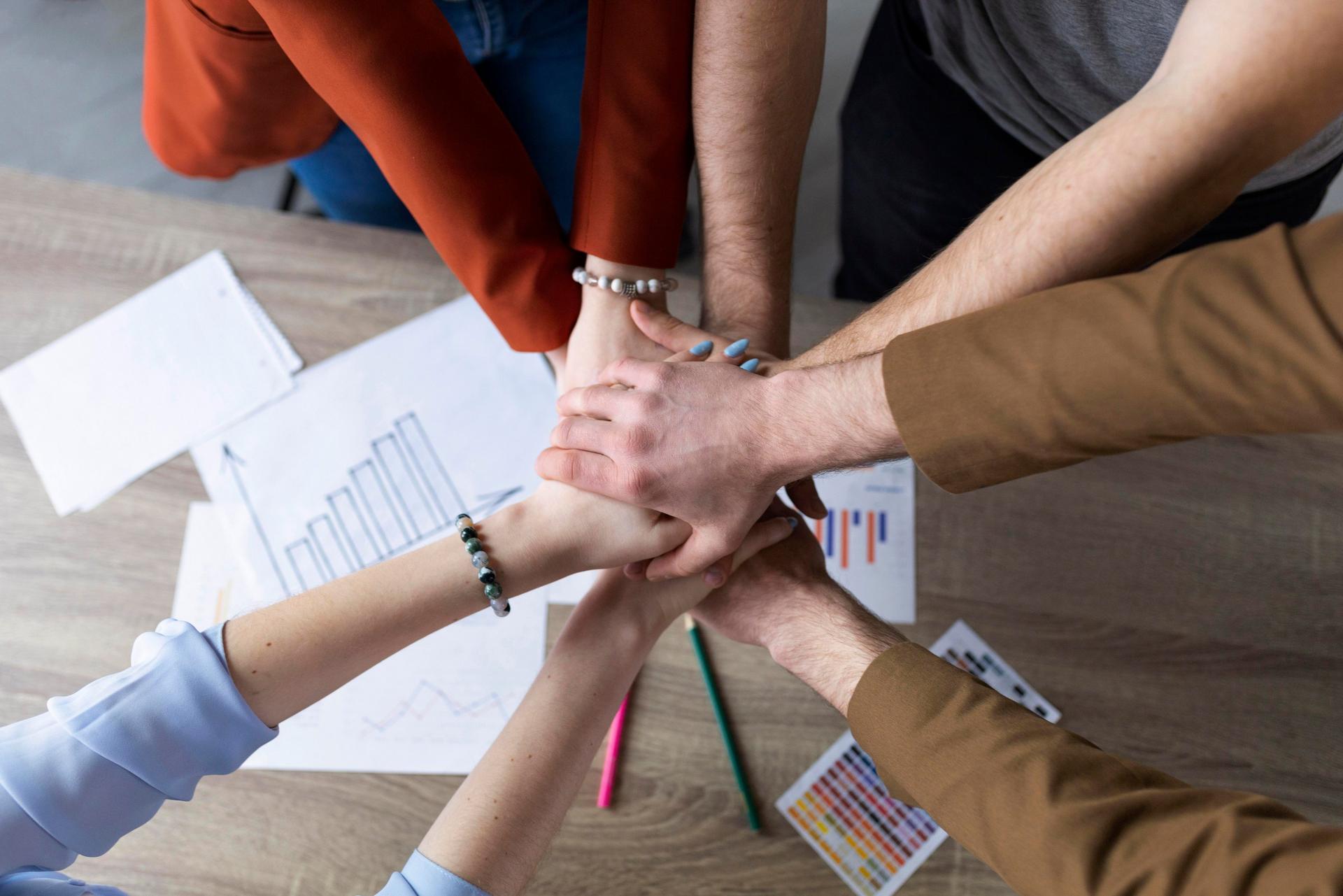 group of coworkers joining hands in a circle