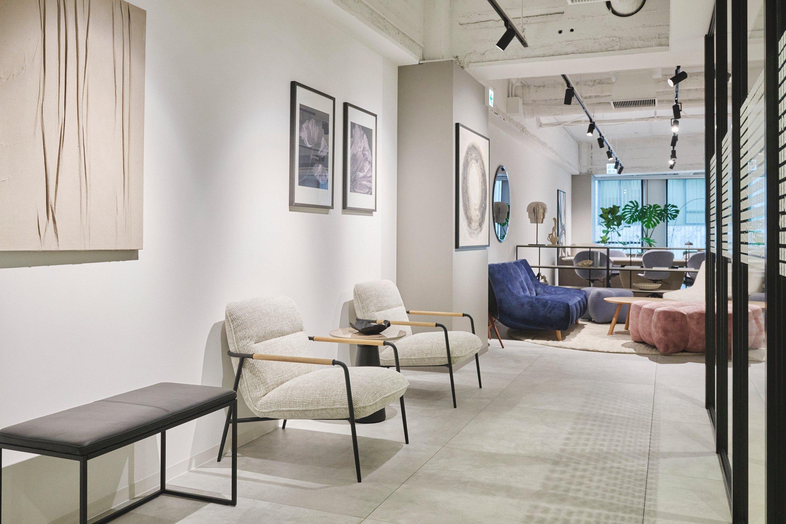 Sala moderna con sillones, sofá azul, cuadros y plantas. Decoración elegante y luminosa.