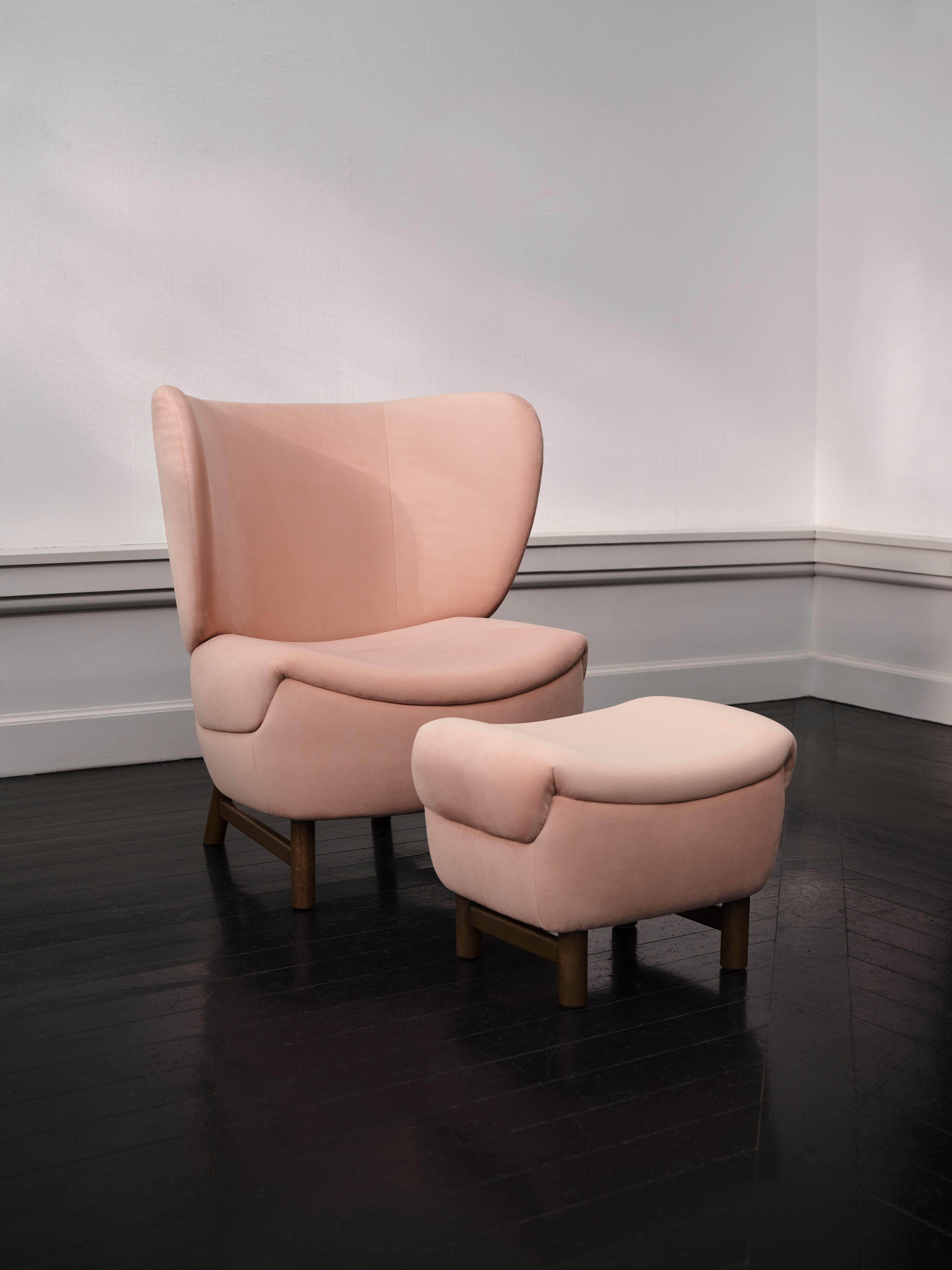 Rosa lenestol med matchende fotskammel, mørke trebent.