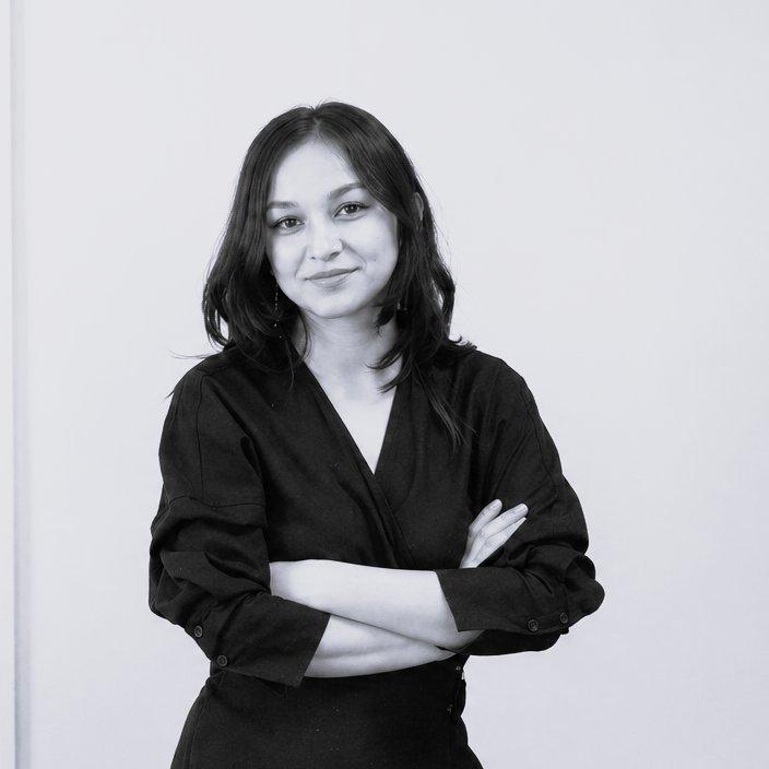 Woman wearing a black wrap-style top with arms crossed.