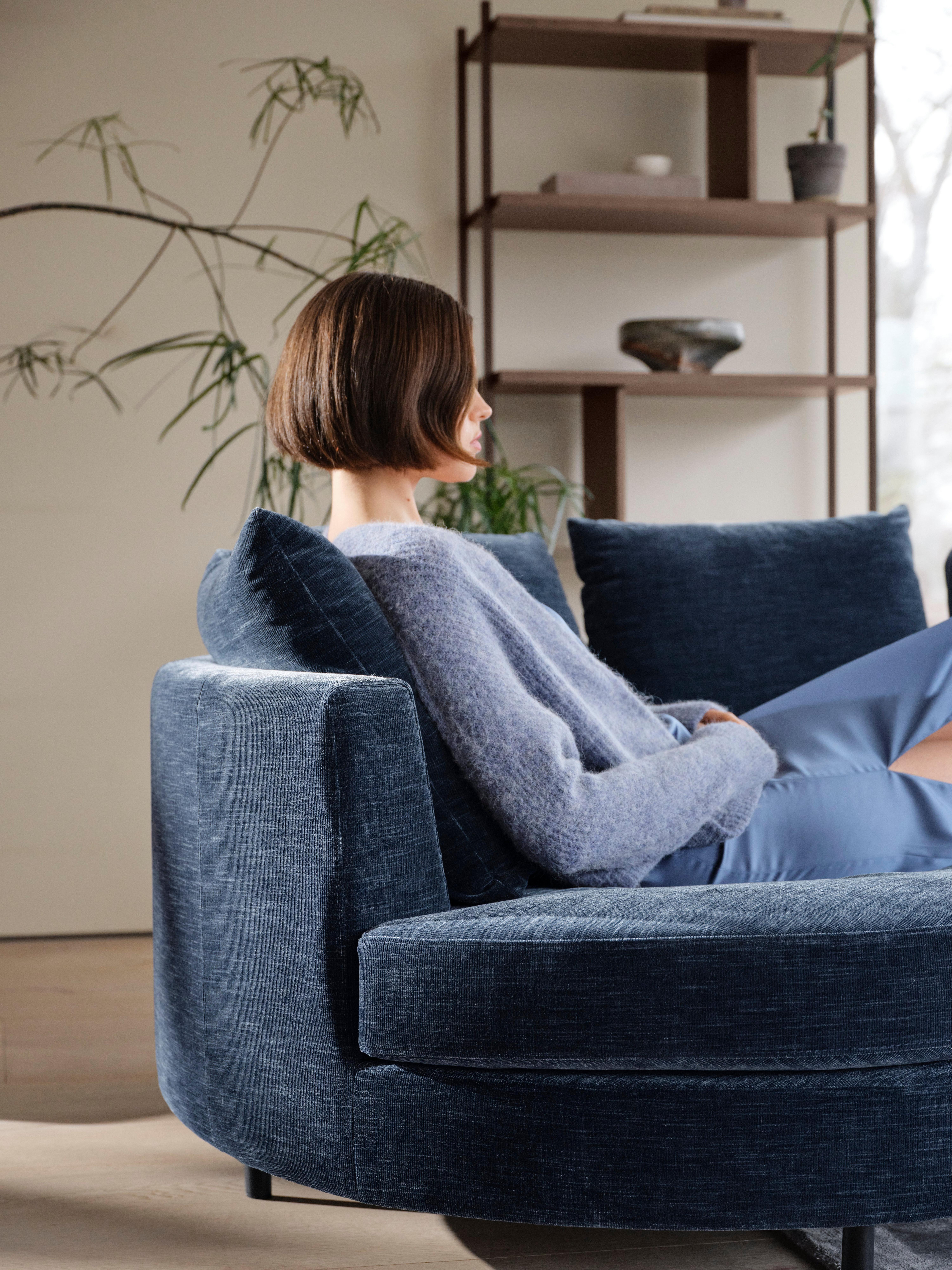 Indivi sofa with chaise longue left, dark blue Napoli fabric, Calgary storage with drawer, dark oak veneer, in the background.