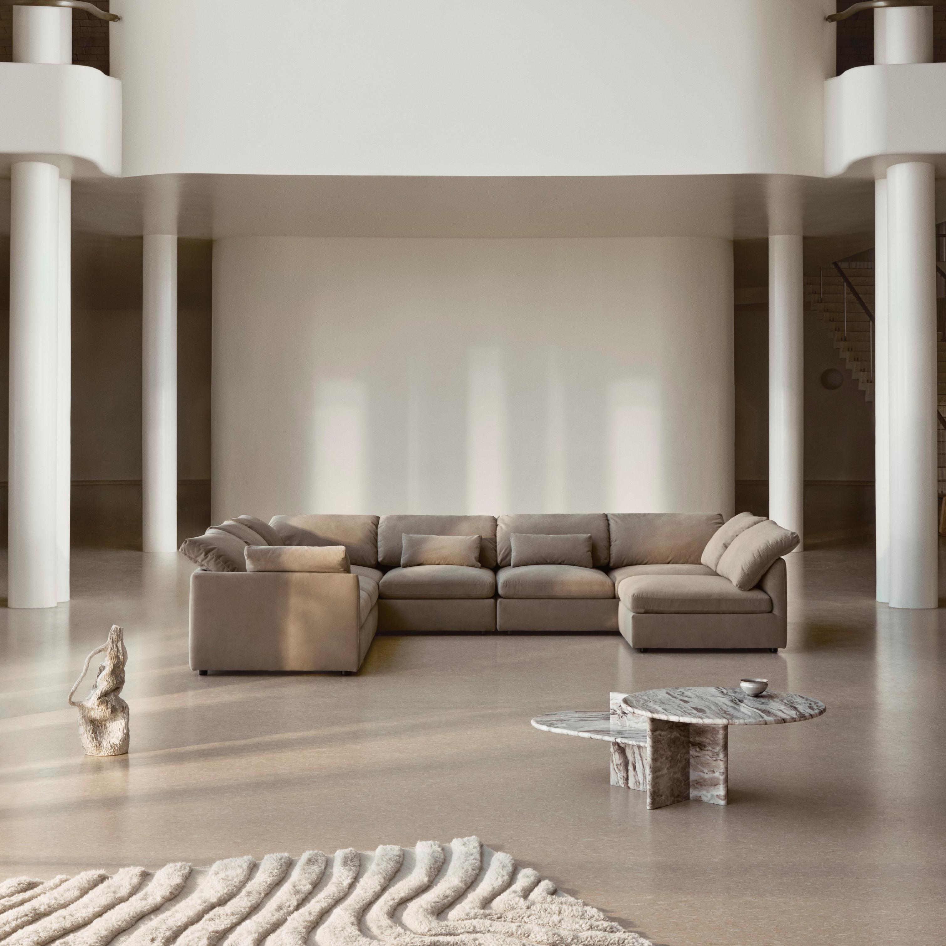 Spacious room with a sand fabric modular sofa, round brown marble coffee table, and cream and grey textured rugs.