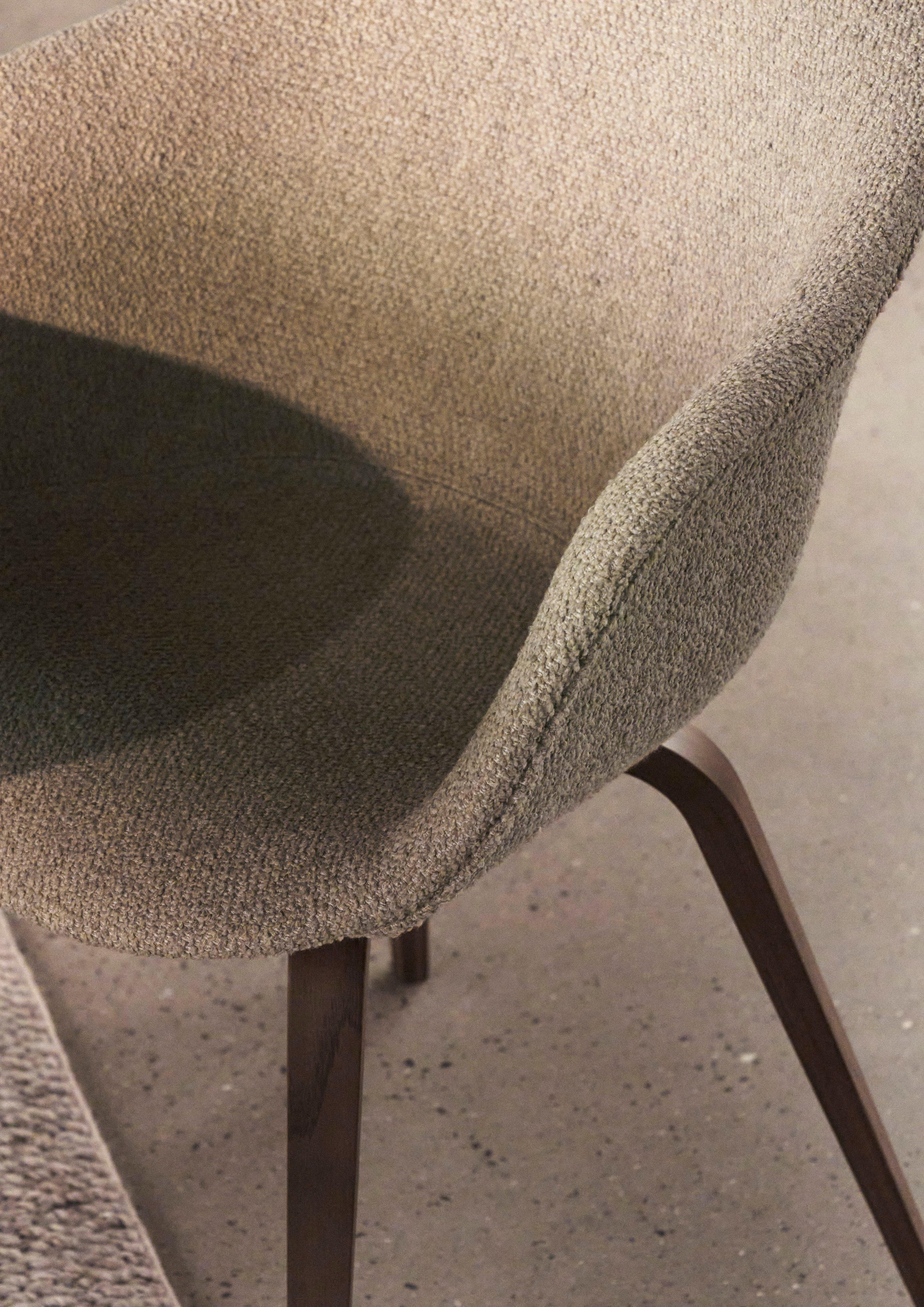 Bliższe spojrzenie na otulające użytkownika krzesło do jadalni Hauge tapicerowane beżową tkaniną Lazio.